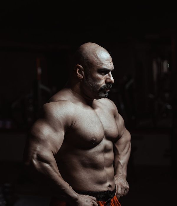 Man performing a powerful strength exercise in a dark, focused environment.